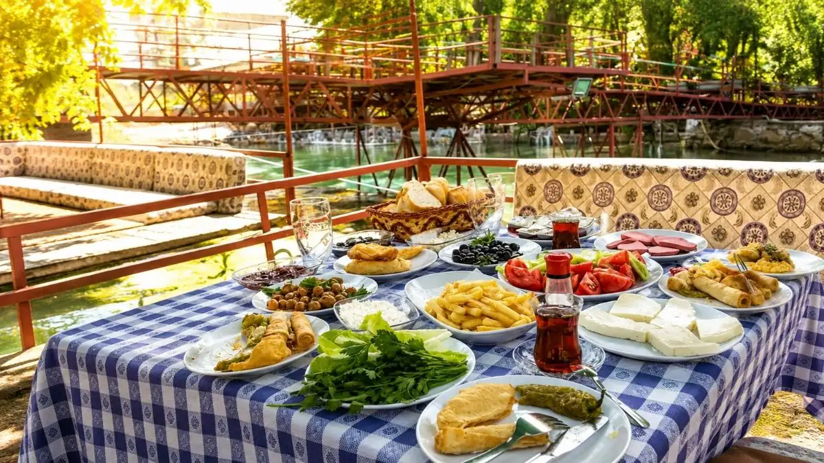 Dim Çayı kenarında ahşap platformda kurulmuş serpme kahvaltı sofrası