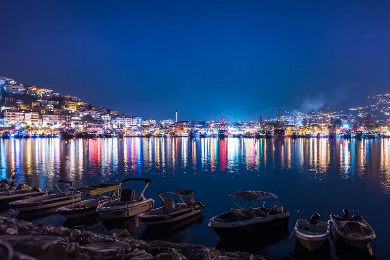 Alanya limanında gece tekneler ve renkli ışık yansımaları