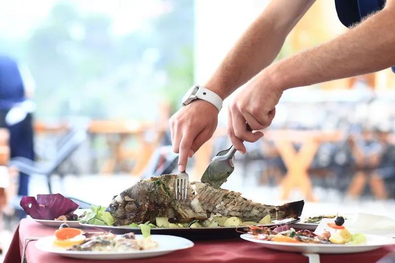 Garsonun masada balığı ayıklayıp servis etmesi