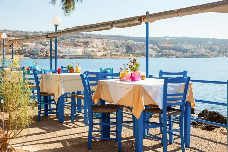 Deniz kenarında mavi sandalyeli balık restoranı masaları